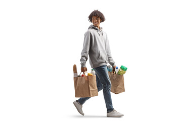 full length portrait of a young african american man arrying grocery bags walking and looking back