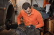 © Galka3250 - Mechanic man repairs the undercarriage of the car. A man repairs a car in a garage. Car wheel repair