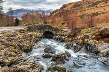 Ashness Bridge, With The Snow Covered Mountain Of Skiddaw In The Distance, Near Keswick And Derwent Water In The Lake District National Park, England.