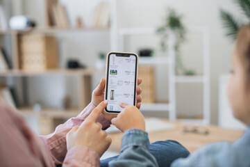 Close up view of woman and girl hands with french braids sitting at home and purchasing fast food online. Mother and daughter spending time together while using mobile phone for e-commerce.