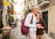 Joyful Senior Tourists Couple Hugging Posing With Backpack Outdoors