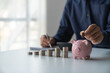 © Phimwilai - Budget and money saving concept for future planning accounting. Male hand putting coins in piggy bank Financial plan and money saving concept business finance and investment life and family planning.