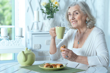 Poster - beautiful smiling old woman drinking tea with cookies