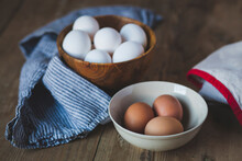 Close-up Of Eggs In Bowls With Napkin On Wooden Table