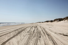 Tire Track On Sandy Beach Against Clear Sky During Sunny Day