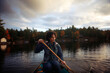 © Cavan Images - Woman canoeing on lake against cloudy sky during sunset