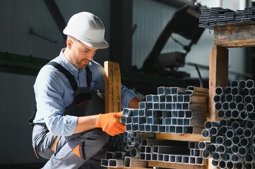 Wall Mural - Portrait of factory worker in protective uniform and hardhat standing by industrial machine at production line. People working in industry