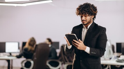 Wall Mural - Handsome businessman using tablet. Indoor shot of focused office manager with digital device