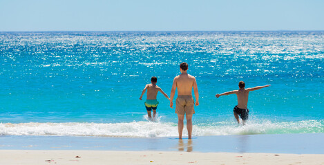 Wall Mural - Young male vacationers on Camps Bay beach, Cape Town