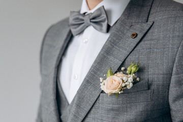 Wall Mural - A man with a beard in a stylish suit with a watch on his arm fixes a bow tie. Morning of the groom. Close up detail of man suit for wedding