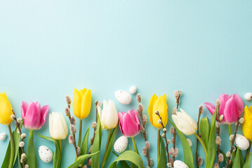 Wall Mural - Easter atmosphere concept. Top view photo of easter eggs pussy willow branches yellow pink and white tulips on isolated pastel blue background with empty space