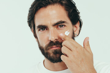 Wall Mural - Man applying facial cream on his face, keeping it smooth and hydrated