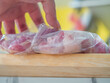 Closeup of raw pork meat in plastic bag on wooden cutting board in the kitchen. Portion cooking preparation for freezing food.