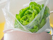 Closeup of fresh green lettuce in plastic bag with pink plastic bowl in the kitchen. Healthy food and diet concept.