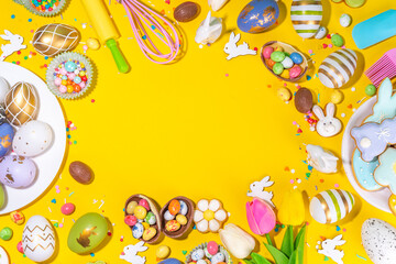 High-colored Easter baking background, Easter sale, party invitation flatlay, Colorful Easter eggs, chocolate eggs and bunny rabbit with sugar sprinkles on bright yellow background top view copy space