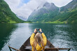 © AILA/peopleimages.com - Adventure woman in row boat taking photo on smart phone of beautiful fjord lake for social media