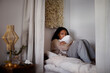 © Johnér - Pensive young woman sitting on bed and hugging pillow