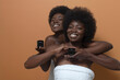 © ADDICTIVE STOCK - Cheerful black women showing bottles of cosmetic