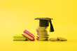 Graduated cap with coins on yellow background. Savings for education, school allowance or financial literacy concept