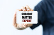 Subject matter expert text on blank business card being held by a woman's hand with blurred background. Business concept about subject matter expert.