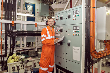 Young offshore professional engineer checking parameters of high voltage switch board. Offshore engineer making high voltage electrical equipment checks.