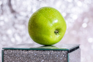 Closeup of ripe round green apple on shiny glass surface