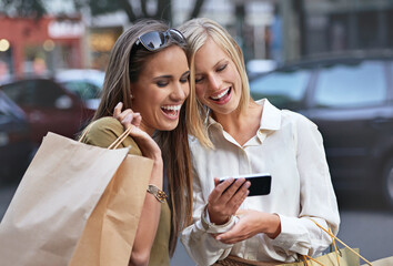Aufkleber - Theres a sale on at our favorite shop. A woman showing her friend something on a cellphone while theyre out shopping in the city.