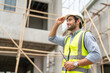 © Supachai - Portrait of male civil engineer wear safety vest with white helmet holding walkie talkie walking to inspection housing estate at construction site