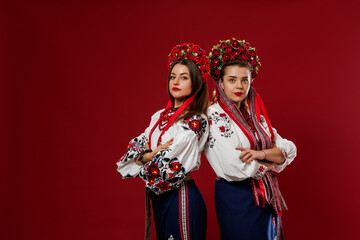 Wall Mural - Ukrainian women in traditional ethnic clothing and floral red wreath on viva magenta studio background. National embroidered dress call vyshyvanka. Pray for Ukraine