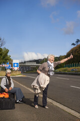 Wall Mural - Making their escape from the retirement village...Two senior ladies hitch-hiking by the side of the road.