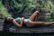 © ADDICTIVE STOCK - Slim woman in bikini lying on tree trunk