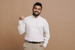 © Drobot Dean - Positive indian man pointing finger at copy space isolated over beige background
