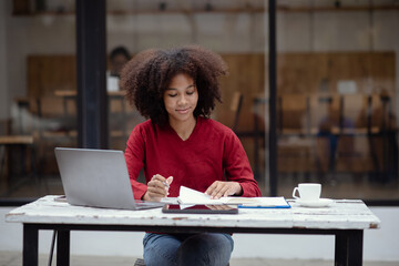 Sticker - Young African American businesswoman working with laptop at cafe.