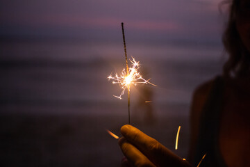 Sticker - woman holding sparkles celebrating on tropical beach