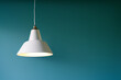 Lamp with a white lampshade hanging on the cable in a room with soft background