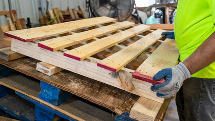 Wooden pallets Manufacturing with worker building pallet in warehouse