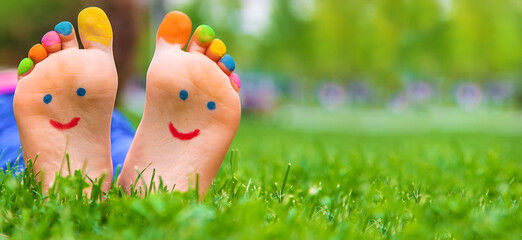 Feet of a child on the grass with a painted smile. Selection focus.