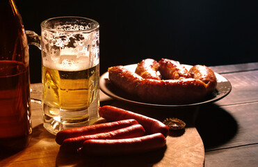 Beer in glasses and fried sausages on a wooden table surface, close-up. Beer and beer snacks.