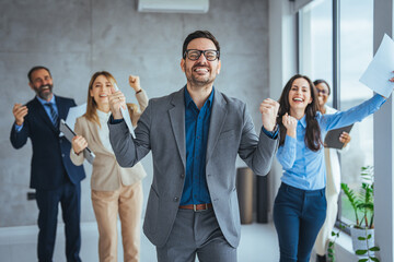 hot of a group of young businesspeople standing together and clapping in a modern office. Shot of colleagues celebrating during a meeting in a modern office. 