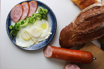 Canvas Print - breakfast sausage ham egg scrambled eggs salad cucumber on a plate view from above on a white background. breakfast at the hotel Healthy food