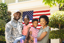 Portrait Of Happy African American Soldier And His Family Embracing, Holding Usa Flags