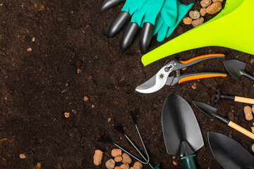 Wall Mural - Gardening tools, pruner, gardening gloves, shovel and rake on soil background. Conceptual composition of the garden. Place for text. Place to copy. The concept of gardening and hobbies. gardening Tool