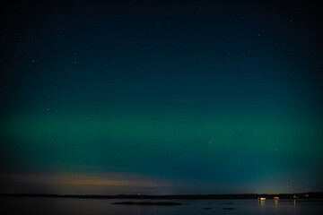 Green northern lights over a fjord.