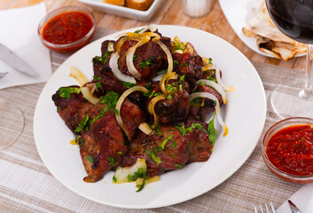 Wall Mural - Oriental grilled pork meat shashlik with sliced onion rings on a white ceramic plate