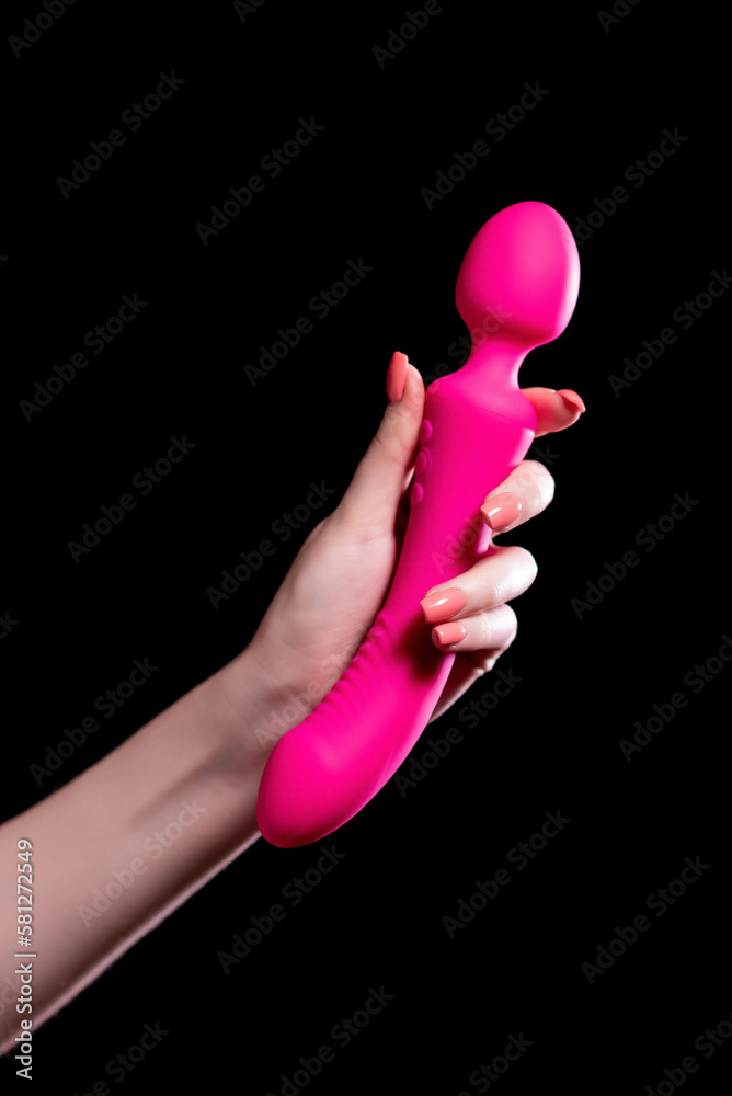 The girl's hand holds a pink massager for sex on a black isolated  background. Vibrator for masturbation. Dildo for stimulation. Image for sex  shop Stock Photo