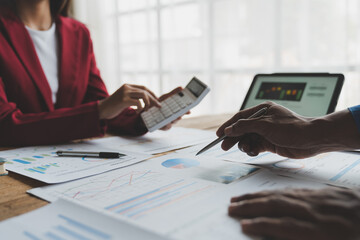 Group of businessmen, investors brainstorming financial reports with calculators to calculate income, taxes, accounting from graphs, growth charts, real estate projects to prepare for meeting results