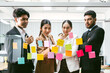 © artitwpd - Group of successful Asian businessmen teamwork. Brainstorm meeting with sticky paper notes on the glass wall for new ideas. Using agile methodology for business in a tech start-up office.