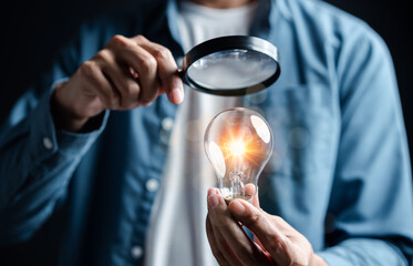 Businessman focus with magnifying to light bulb with business target planning idea and creativity innovation development leadership investment growth and success development, goal, strategy