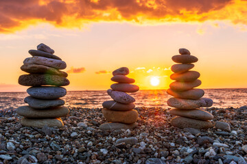 three towewrs or turrets of stone in a nice empty sea beach with coast line guring sunset or sunrise with amazing cloude sky on baclground