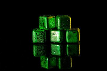 Wall Mural - Green Stainless steel cubes simulating ice for cooling drinks on a black surface with a reflection.